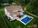 Aerial view showcasing a beautiful home with a sparkling pool, patio, and lush green yard at 6505 Folger Dr, Charlotte, NC 28270