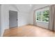 Minimalist bedroom with hardwood floors, a gray door, and a large window overlooking green scenery at 6505 Folger Dr, Charlotte, NC 28270