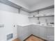 Well-lit laundry room with gray cabinets, a white countertop, open shelves, and hardwood flooring at 6505 Folger Dr, Charlotte, NC 28270