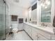 This bathroom offers a double sink vanity, marble tile floors, a glass shower, and a built-in television at 676 Cottingham Ne Pl, Concord, NC 28025
