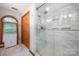 This bathroom features a glass enclosed shower with marble tile, shelving, and a wooden closet at 676 Cottingham Ne Pl, Concord, NC 28025