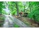 View of a two-story home with mature landscaping and wooden exterior, up a sloping driveway at 676 Cottingham Ne Pl, Concord, NC 28025