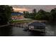 Aerial view of a luxurious lakeside home with a private dock, boat, and jet skis, set against a scenic backdrop at 8170 Bay Pointe Dr, Denver, NC 28037