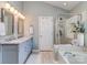 Luxurious bathroom featuring double sinks, vanity, glass shower, and a soaking tub at 9422 Olivia Ln, Charlotte, NC 28277