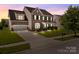 Charming brick two-story home with a manicured lawn and attached two-car garage at twilight at 9937 Violet Cannon Nw Dr, Concord, NC 28027