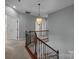 Staircase and hallway featuring wood and iron railings and a modern pendant light fixture at 9937 Violet Cannon Nw Dr, Concord, NC 28027