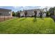 Expansive backyard with lush green lawn, mature trees, and well-defined fencing at 10211 Dominion Village Dr, Charlotte, NC 28269
