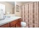Cozy bathroom with warm tones, a single vanity, and a shower-tub combination with a patterned curtain at 10211 Dominion Village Dr, Charlotte, NC 28269