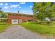 Backyard view of home with a garage, graveled parking area, and mature trees at 1321 Arbor Dr, Salisbury, NC 28144