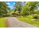 Gravel driveway leads to a metal carport surrounded by lush greenery, with ample parking at 1321 Arbor Dr, Salisbury, NC 28144