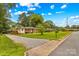Quaint single-story home with inviting front yard, gravel driveway, and appealing landscaping under a bright sky at 1321 Arbor Dr, Salisbury, NC 28144