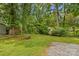 Lush backyard with mature trees, gravel area, and vintage metal garden bench at 1321 Arbor Dr, Salisbury, NC 28144
