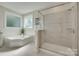 Bathroom featuring a soaking tub, tiled shower, and dual windows for natural light and privacy at 2205 Gallberry Ln, Waxhaw, NC 28173