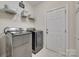 Bright laundry room featuring a washer, dryer, a shelf, and a white door at 2205 Gallberry Ln, Waxhaw, NC 28173