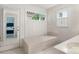 Bright bathroom features a tiled tub, double windows and white cabinets at 2308 Blair House Ct, Charlotte, NC 28270