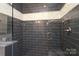 Close up of a glass-enclosed walk-in shower with gray tile and bench seating at 4126 Tyndale Ave, Charlotte, NC 28210
