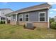 Rear exterior view with brick foundation, vinyl siding, lush lawn, and mature landscaping at 4427 Poplin Grove Dr, Indian Trail, NC 28079