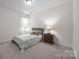 Cozy bedroom with a comfortable bed, nightstand with lamp, and large window with natural light at 4427 Poplin Grove Dr, Indian Trail, NC 28079