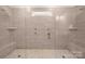 Modern shower with stone-look tile, multiple shower heads, and seating at 4427 Poplin Grove Dr, Indian Trail, NC 28079