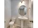 Powder room with a pedestal sink, round mirror, and modern fixtures at 5033 Mockernut Ln, Indian Land, SC 29707