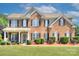 Charming brick two-story home featuring a well-manicured lawn, black shutters, and a welcoming front porch at 604 Palmerston Ln, Waxhaw, NC 28173