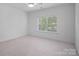 Well-lit bedroom with neutral carpet, a ceiling fan, and a window offering outdoor views at 8303 Adrian Ct, Charlotte, NC 28270
