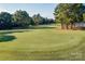 Scenic view of a manicured green golf course with mature trees and a red flag marking the hole at 10043 Tepa Pl, Tega Cay, SC 29708