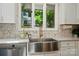 Well-appointed kitchen featuring a stainless steel farmhouse sink, modern faucet, and stylish backsplash at 10043 Tepa Pl, Tega Cay, SC 29708
