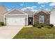 Charming one-story home featuring stone accents, a two-car garage, and a well-manicured front yard at 10410 Bradstreet Commons Way, Charlotte, NC 28215
