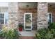 Inviting front entrance with a stone-accented porch, a glass door and a red potted plant at 112 E Neel Ranch Rd, Mooresville, NC 28115