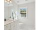 Bright bathroom featuring white tile floors, vanity with storage, and a window at 11234 Villa Trace Pl, Charlotte, NC 28277