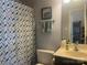 A clean full bath with a white sink, blue vanity, decorative shower curtain, and great lighting at 1177 Triece Ln, Charlotte, NC 28215
