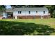 Spacious backyard view of a white house with a brick foundation and covered porch at 1327 Mount Ulla Hwy, Mooresville, NC 28115