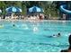 An outdoor swimming pool has swimmers and blue umbrellas at 1418 Skidaway Nw St # 427, Concord, NC 28027