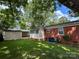 View of a lush backyard featuring a red brick house, a detached garage, and ample green space at 208 S Thompson St, Monroe, NC 28112