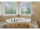 Bright bathroom featuring a garden tub with tile surround and views of a wooded landscape at 274 Cove Creek Loop, Mooresville, NC 28117