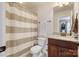 Cozy bathroom featuring a shower-tub combination with a striped shower curtain, granite countertops, and wooden cabinets at 274 Cove Creek Loop, Mooresville, NC 28117