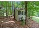Exterior view of storage shed tucked away into the trees with neutral siding and a dark shingled roof at 274 Cove Creek Loop, Mooresville, NC 28117