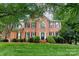 Stately brick residence with lush green lawn, mature trees, and symmetrical facade with black shutters at 3112 Planters Ridge Rd, Charlotte, NC 28270