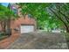 Spacious driveway leads to a two-car garage, surrounded by mature trees and lush greenery at 3112 Planters Ridge Rd, Charlotte, NC 28270