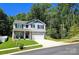 Two-story home featuring stone accents, light gray siding, black shutters, and a two-car garage with lush greenery background at 3816 Rosewood Dr, Mount Holly, NC 28120