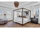 Bright bedroom with a four-poster bed, wood floors, decorative chandelier and a comfortable lounge chair at 394 Stonecliff Ln, Clover, SC 29710