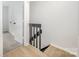 Upstairs hallway featuring gray carpeting, laminate stairs, and black banister at 3941 Briarhill Dr, Charlotte, NC 28215