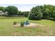 A landscaped backyard features a fire pit, Adirondack chair, and mature trees at 7006 Lone Eagle Dr # 18, Monroe, NC 28110