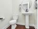 Clean powder room with hardwood floors, pedestal sink, and a round decorative mirror creating a comfortable space at 7011 Hyde Park Dr, Indian Trail, NC 28079