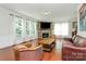 Comfortable living room featuring hardwood floors, a stone fireplace, a TV, and natural light streaming through the windows at 7011 Hyde Park Dr, Indian Trail, NC 28079