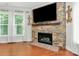 Living room with hardwood floors, a stone fireplace, a TV, and natural light streaming through the windows at 7011 Hyde Park Dr, Indian Trail, NC 28079