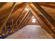 View of the attic showing the exposed wooden beams and plywood floor and window at 8007 Caldwell Rd, Harrisburg, NC 28075