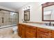 Bathroom featuring double sinks, granite countertops, custom cabinets, and a tiled shower at 8007 Caldwell Rd, Harrisburg, NC 28075