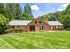 A beautiful brick home has a manicured lawn, trimmed shrubbery, and a classic design with a light-colored roof and dark shutters at 8007 Caldwell Rd, Harrisburg, NC 28075